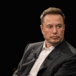 Elon musk sitting in chair looking pensive