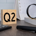 Q2 earnings, desk scene with calculator pen and magnifying glass